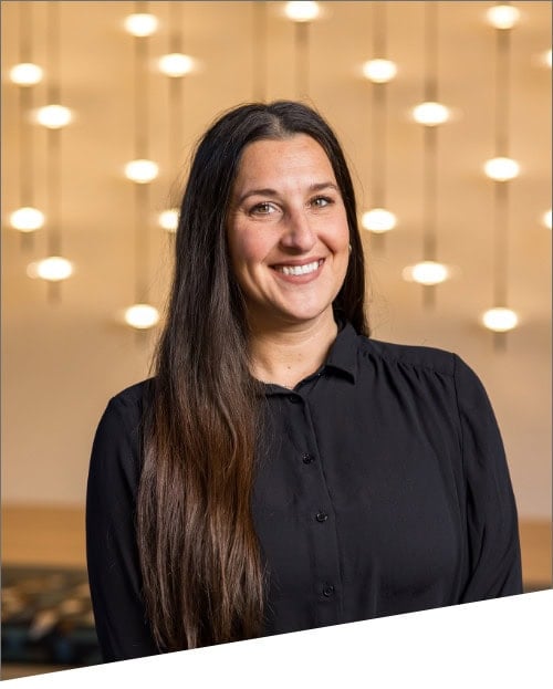 Smiling woman in black shirt with light background.