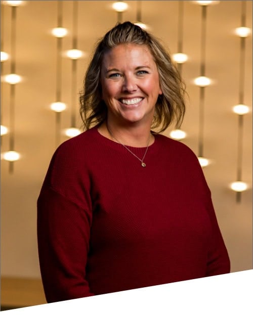 Person smiling in red sweater, lighted background