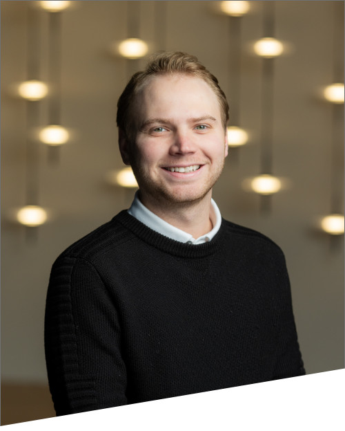 Smiling person in black sweater with blurred lights.