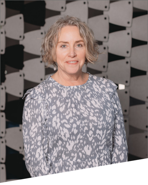 Woman smiling in patterned dress, modern backdrop.
