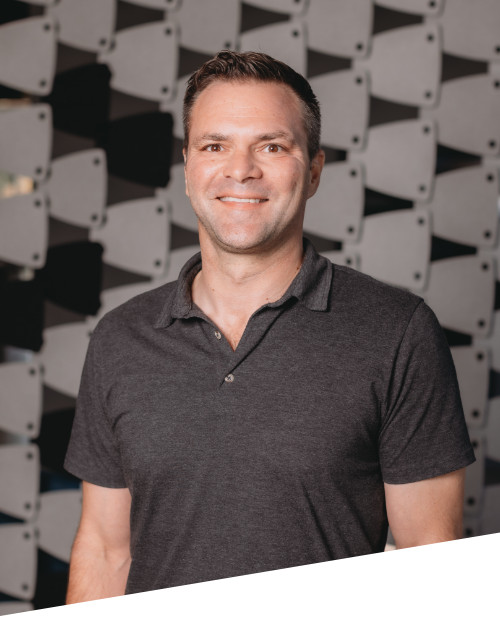 Smiling man in a gray polo shirt indoors.