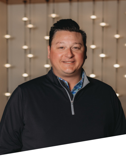Person smiling with decorative lights in background.