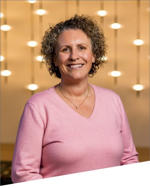 Smiling person in pink sweater with lights background.