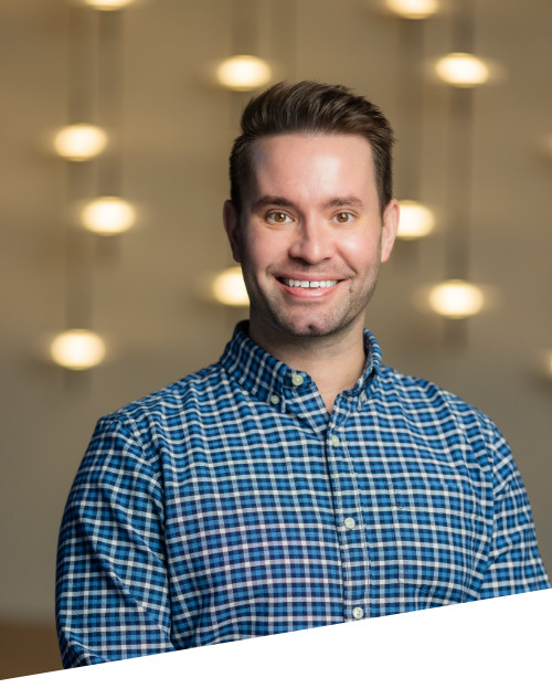 Smiling person in plaid shirt with blurred lights background.