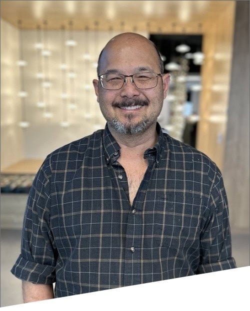Smiling man in checkered shirt indoors.